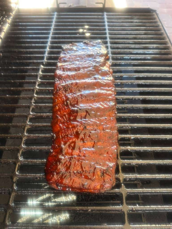 Meat glazed with J. Coleman's BBQ sauce cooking on the grill